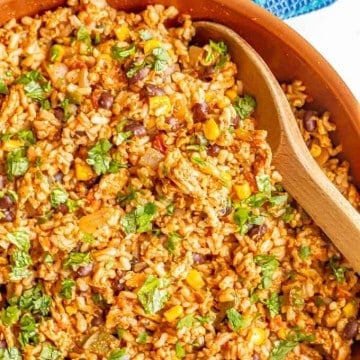 Close up of a wooden spoon in a skillet filled with a ground turkey, rice and bean mixture