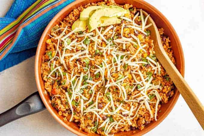 A Mexican turkey and rice skillet with cilantro, cheese and avocado on top