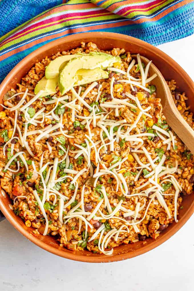 A Mexican ground turkey and rice skillet with cilantro, cheese and avocado on top