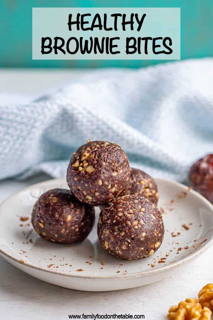 A stack of raw date brownie balls on a plate with a sprinkling of cocoa powder and a text box at top