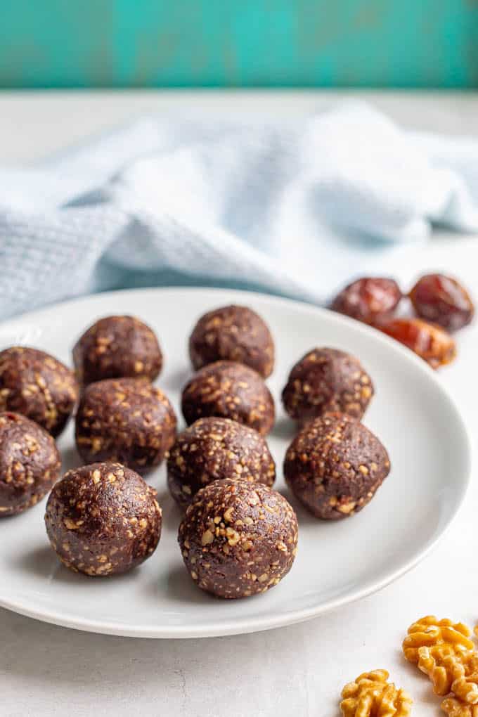 A white plate full of round raw brownie bites made with walnuts and dates