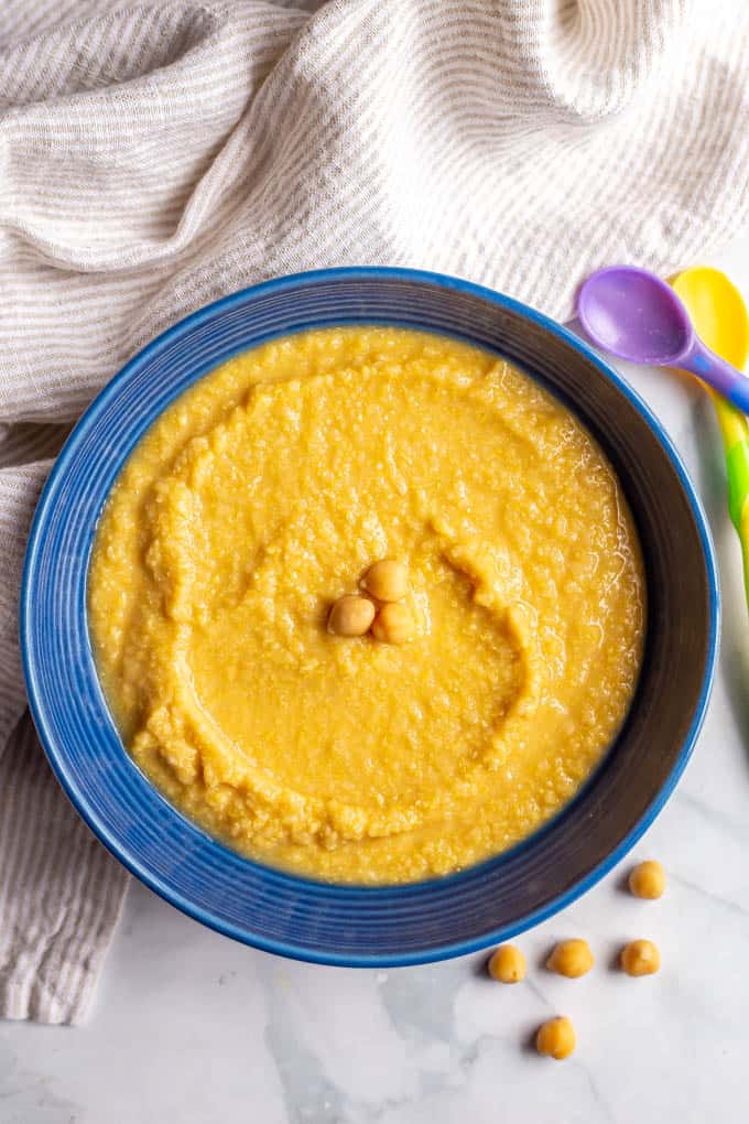 Chickpea puree in a large blue bowl with baby spoons nearby