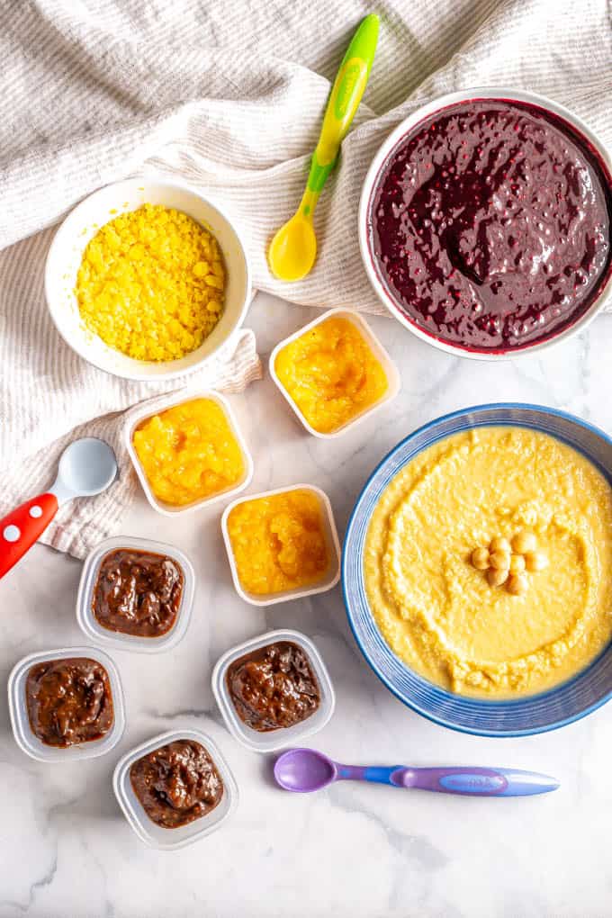 A variety of pureed baby food in different bowls and containers