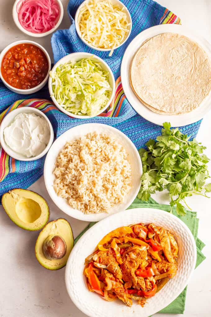 A spread of chicken fajitas with tons of toppings and sides laid out in separate bowls