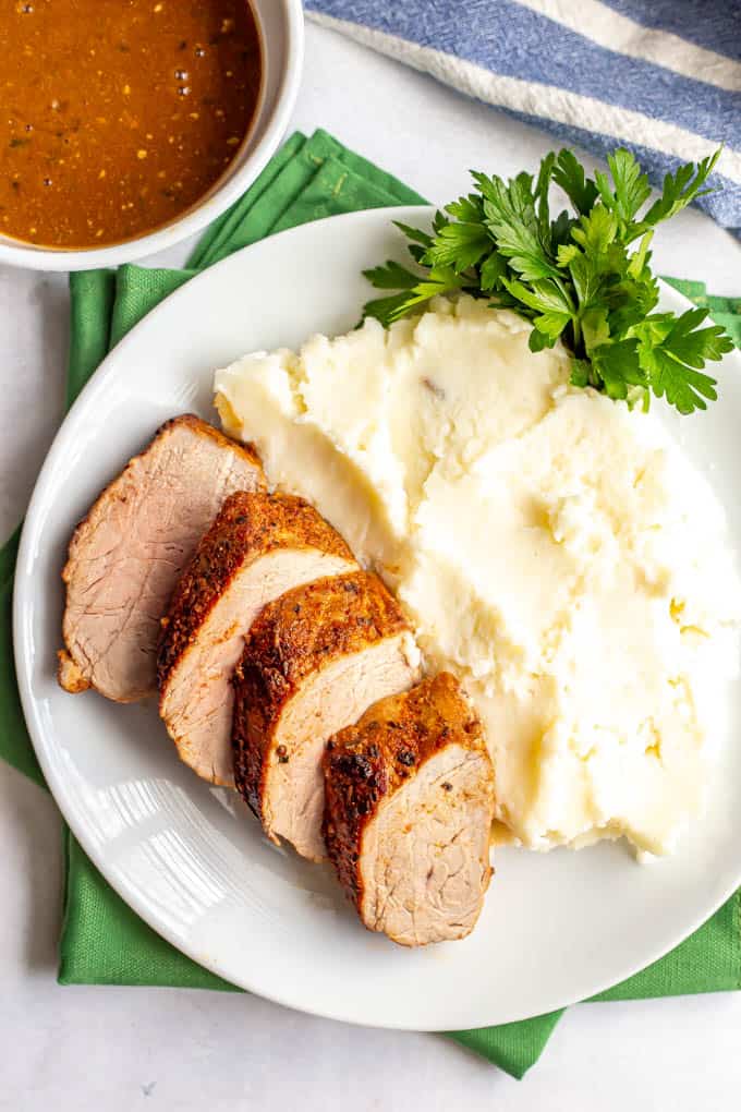 Sliced cooked pork tenderloin plated with mashed potatoes