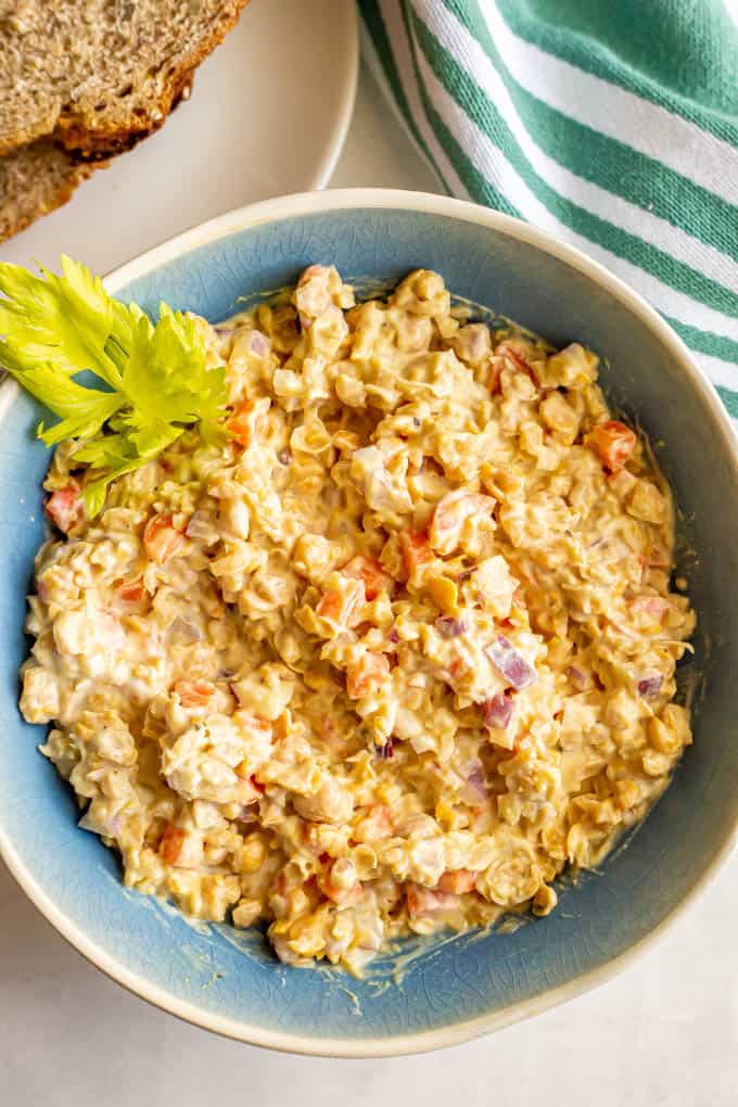 Creamy chickpea salad with carrots and red onion mixed together in a blue bowl