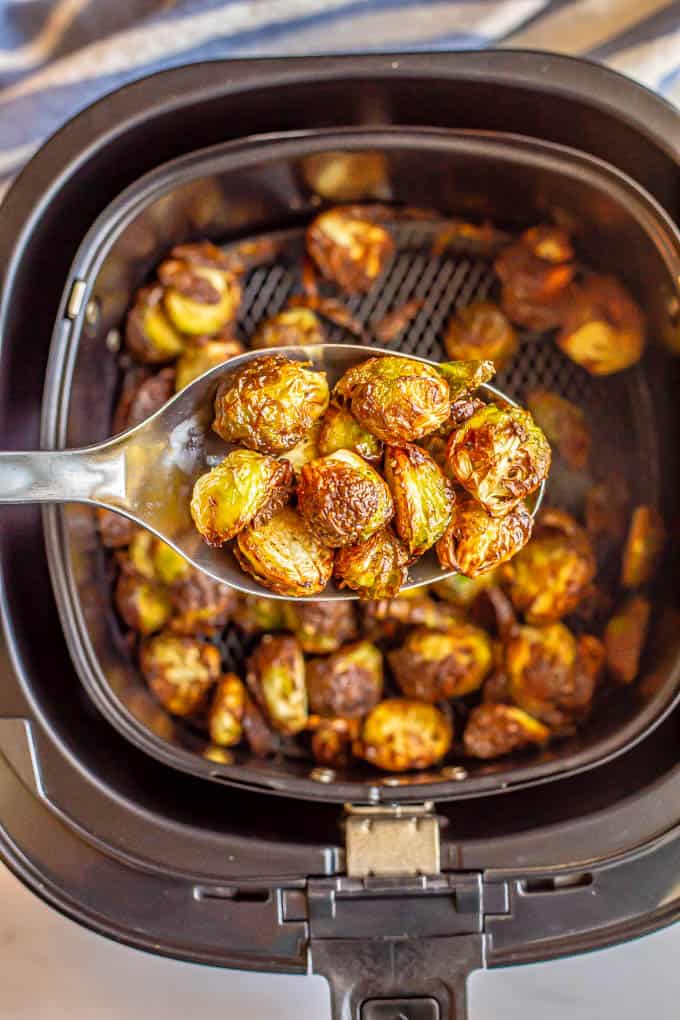 A spoon scooping up some cooked crispy Brussels sprouts from an Air Fryer