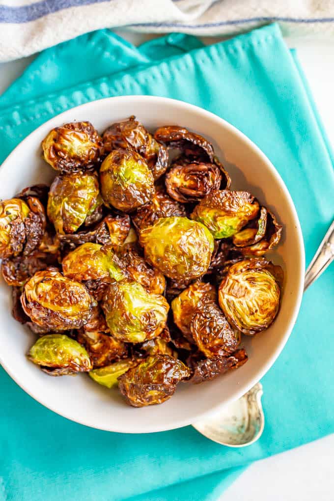 Cooked crispy Brussels sprouts served in a white bowl on turquoise napkins