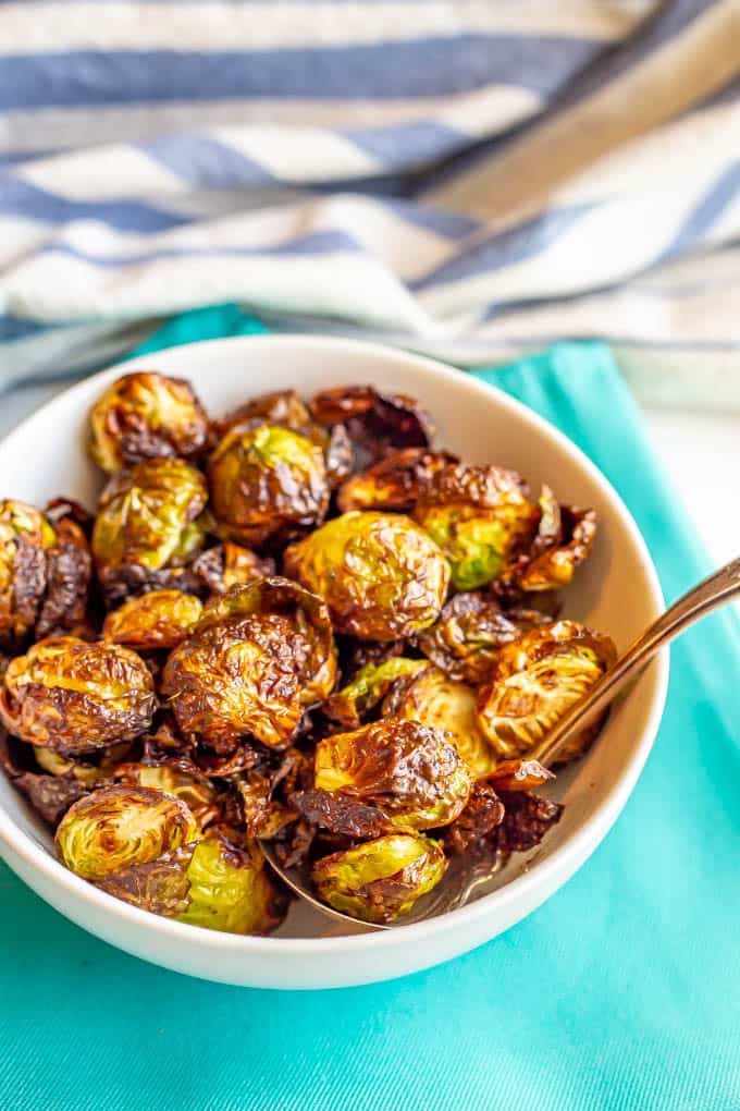 Crispy air fried Brussels sprouts served in a white bowl on turquoise napkins