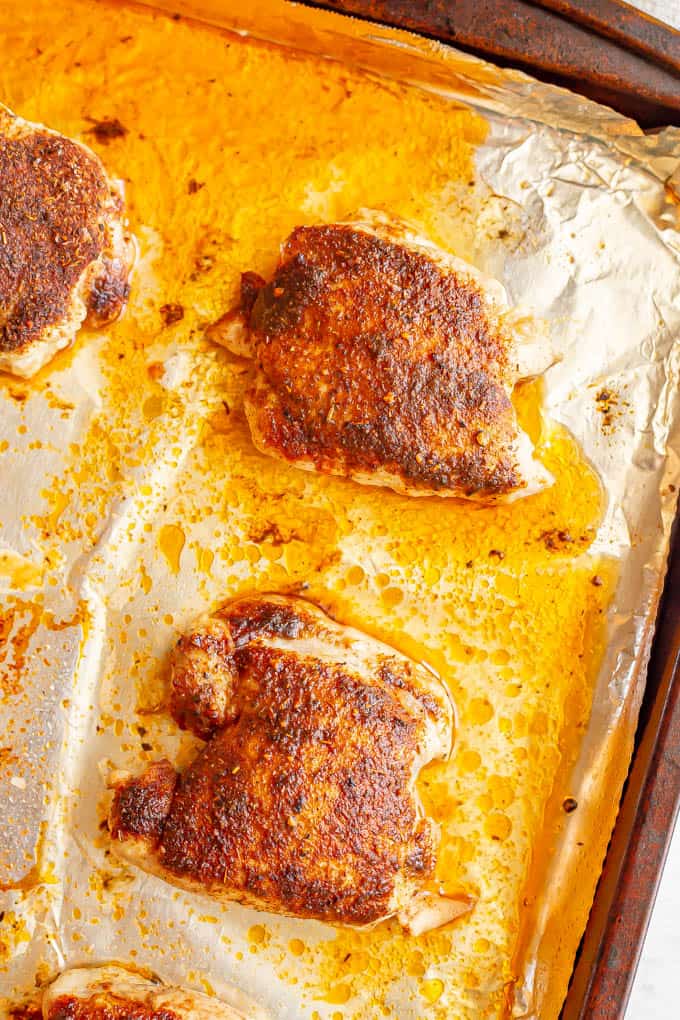 Seasoned chicken thighs in rows on a sheet pan after being baked