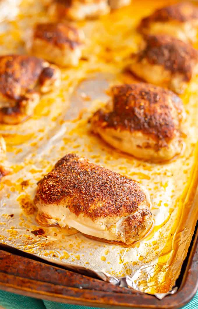 Seasoned chicken thighs in rows on a sheet pan lined with aluminum foil