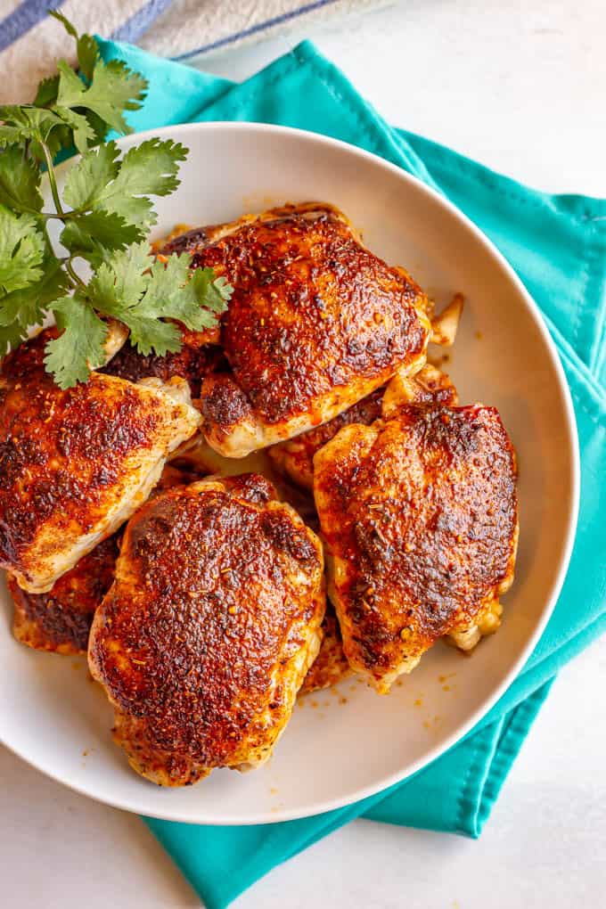 Roasted chicken thighs in a large white bowl set on turquoise napkins