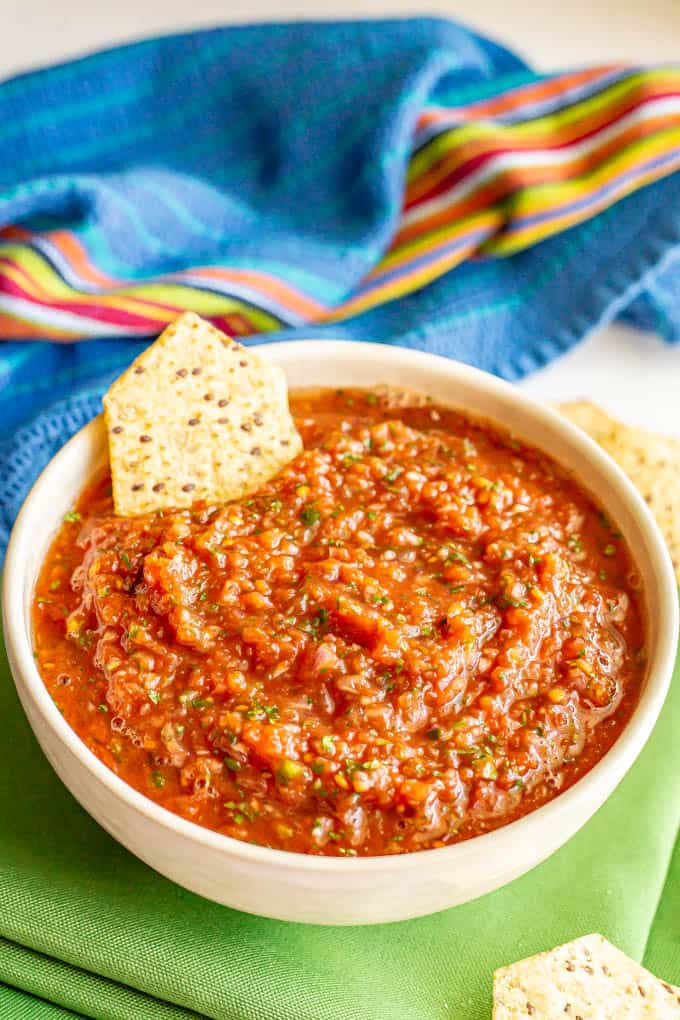 A big bowl of homemade salsa with a chip tucked in the side of the bowl