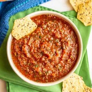 Salsa served in a white bowl with tortilla chips scattered around