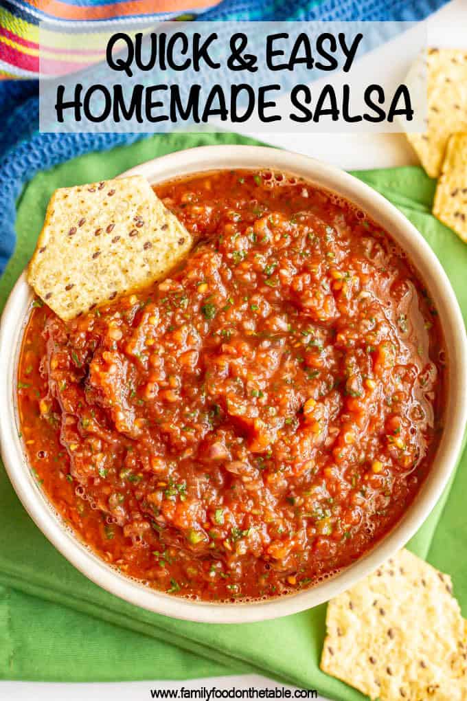 A bowl of salsa with cilantro and jalapeno with a chip for dipping on the side and a text box on top