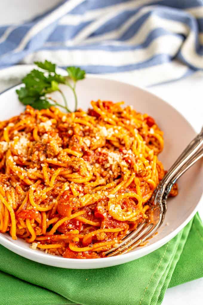 Spaghetti noodles with a meaty tomato sauce in a bowl with two forks tucked in