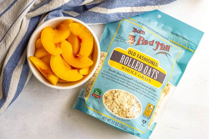 A bowl of sliced peaches and a bag of Bob's Red Mill oats on a counter