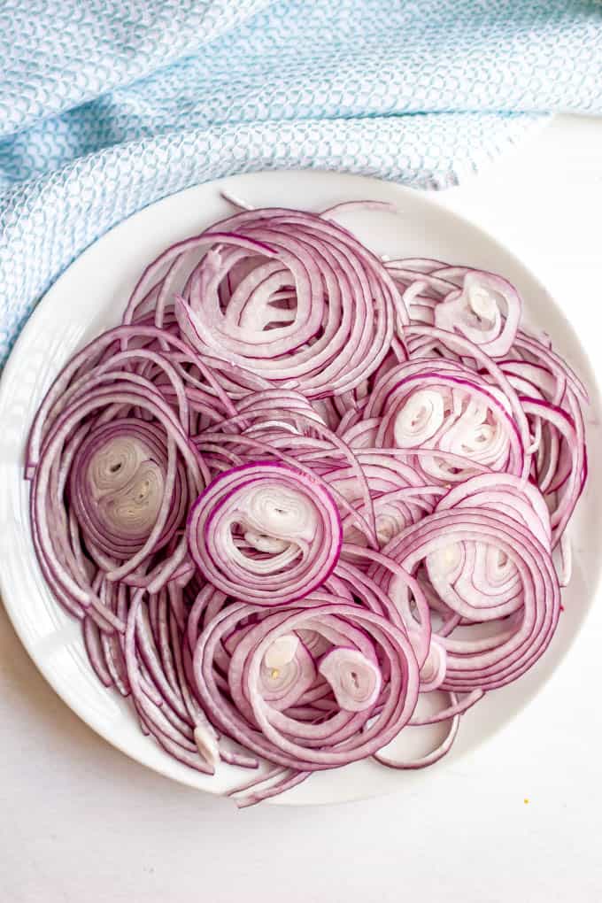 A white plate full of pretty sliced red onion spirals