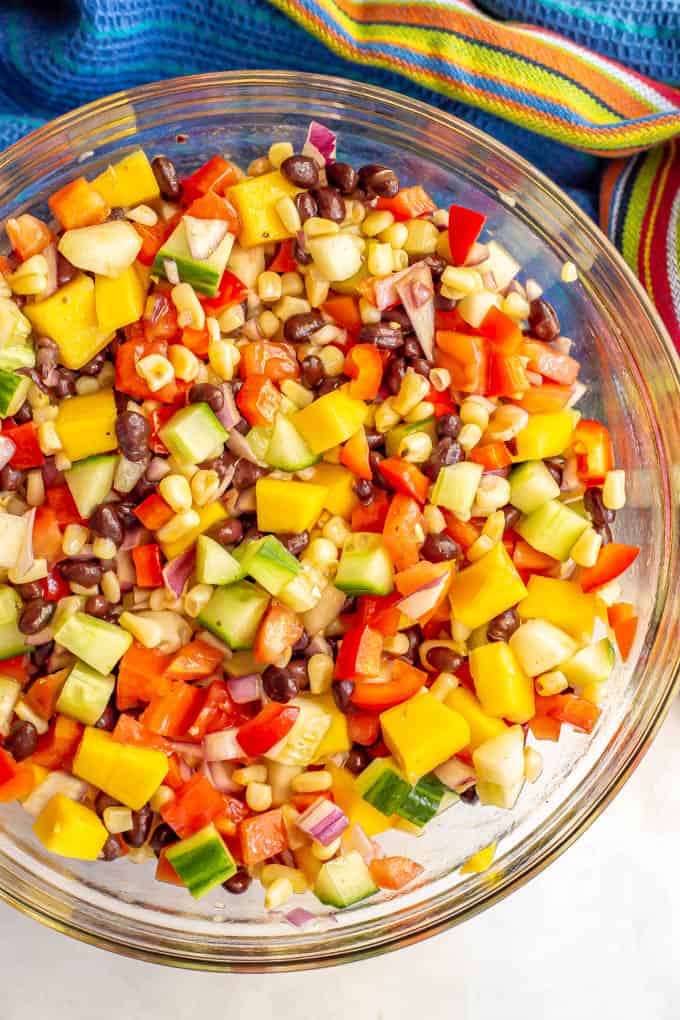 Black bean mango salad with fresh veggies in a large clear glass bowl