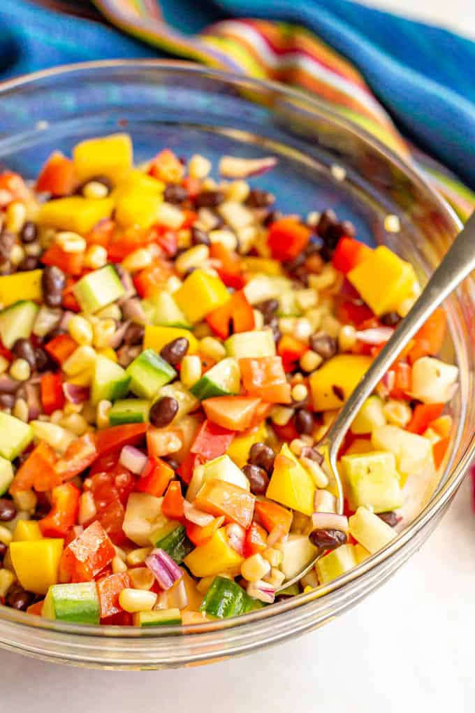 A scoop being taken of a mango and black bean mixed salad