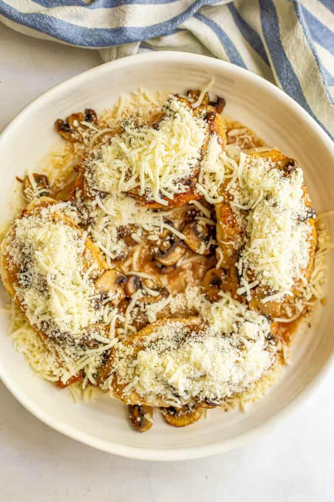 Seared chicken breasts topped with mushrooms and mixed cheeses before being baked