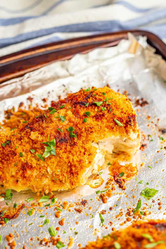 Crunchy golden brown chicken breasts sprinkled with chopped parsley on a sheet pan after baking