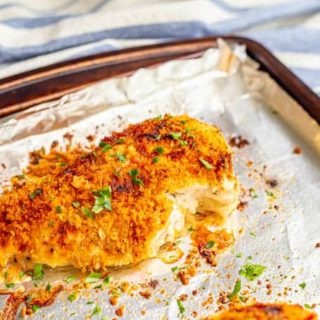 A baked Parmesan crusted chicken breast on a sheet pan lined with aluminum foil