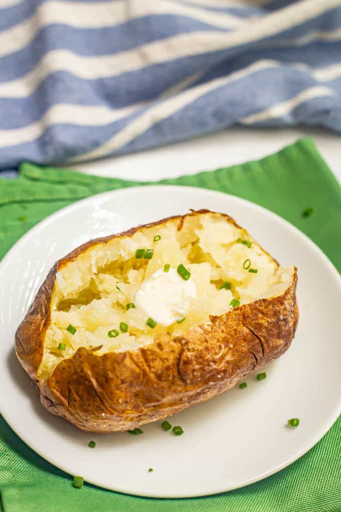 A baked potato served with a pat of butter and a sprinkling of chives