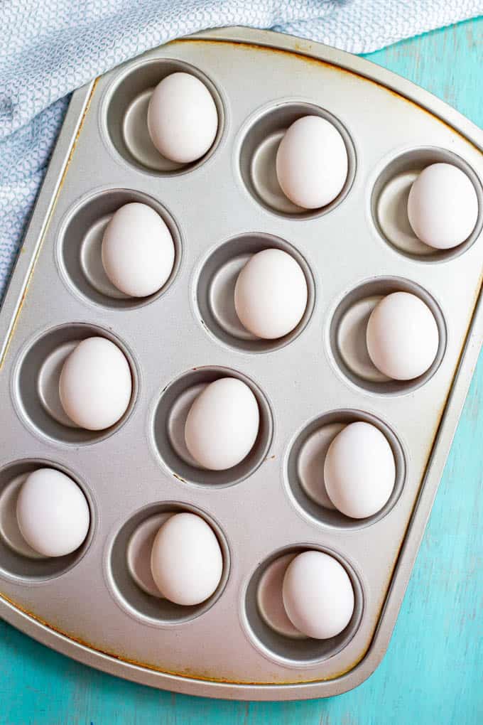 A silver muffin tin with an egg in each cup