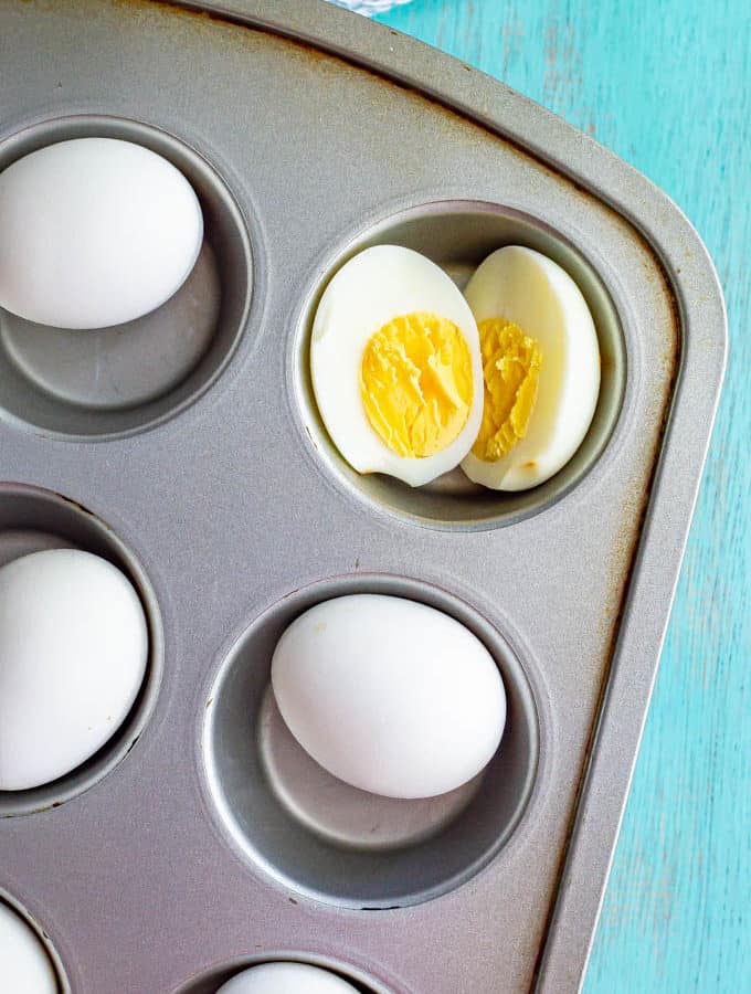 Cooked eggs in a muffin tin with one cut open in half