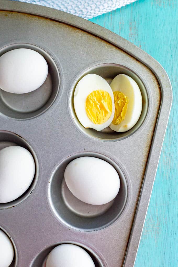 Cooked eggs in a muffin tin with one cut open in half