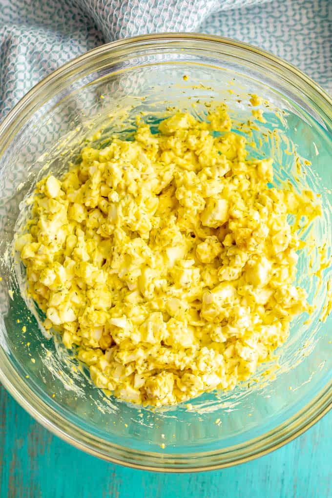 Egg salad mixture in a glass bowl on a turquoise counter