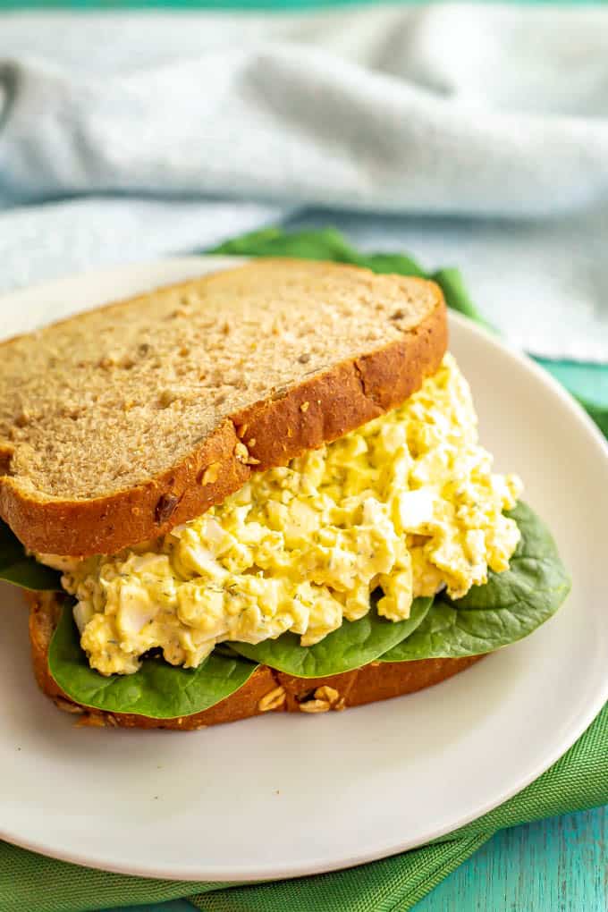 Egg salad sandwich with spinach served on a white plate