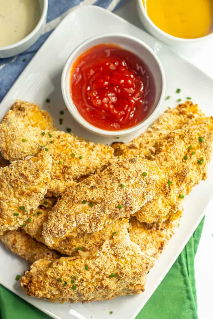 Overhead view of a plate of chicken tenders being served with dipping sauces