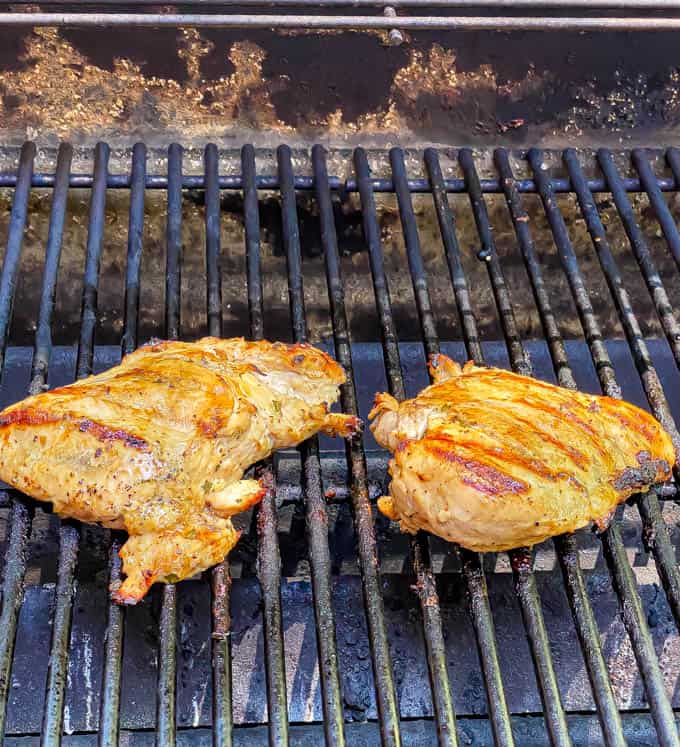 Two chicken breasts being cooked on a grill