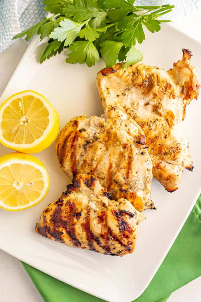 Overhead image of grilled chicken breasts with parsley and lemon on the side