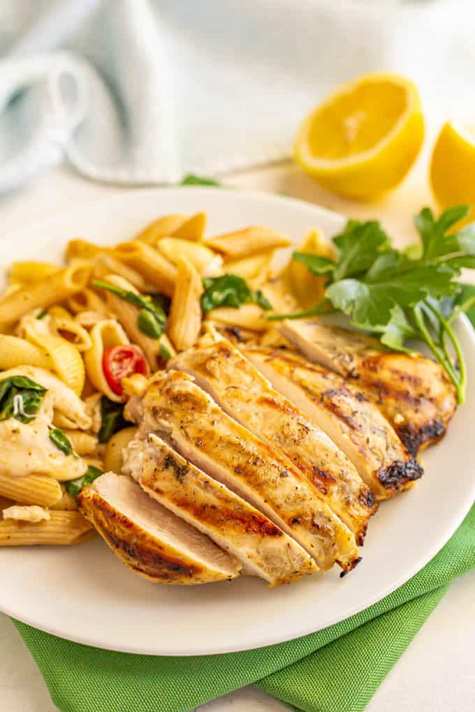 Sliced grilled chicken breast on a dinner plate with a pasta salad