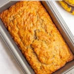 Baked loaf of banana bread in a bread pan with a text box on top