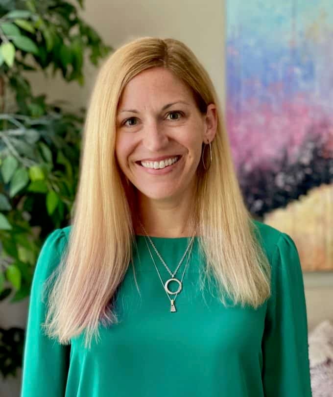 Profile photo of a woman with blonde hair wearing a green shirt