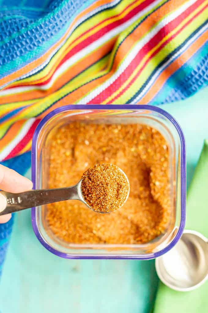 A teaspoon measure scooping up some southwest seasoning out of a clear container