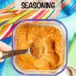 A teaspoon measure scooping up some southwest seasoning out of a clear container