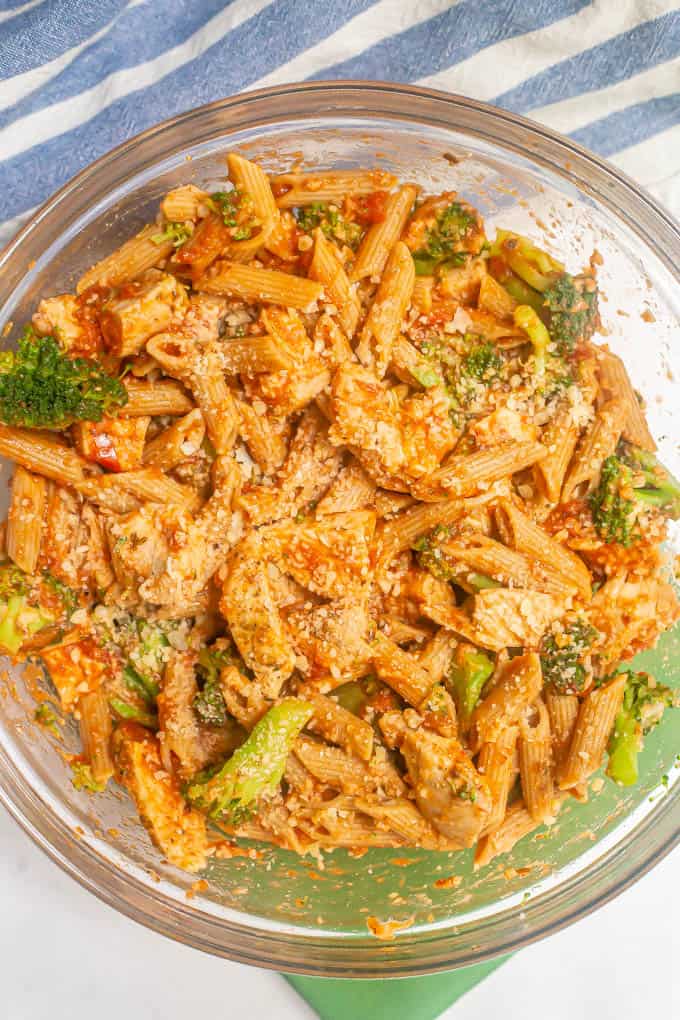 Large glass bowl of a pasta mixture with chicken, broccoli, marinara and Parmesan cheese