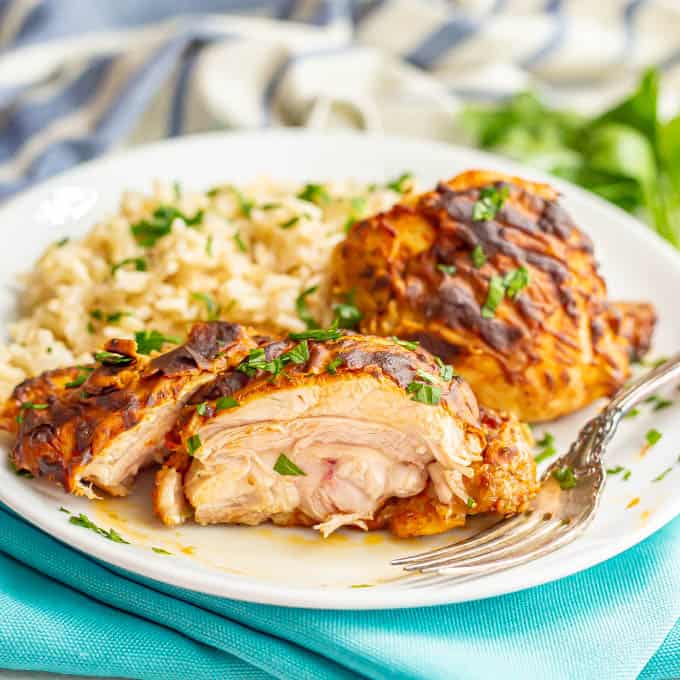 A sliced view of a cooked chicken thigh with dijon mustard and parsley on a white plate