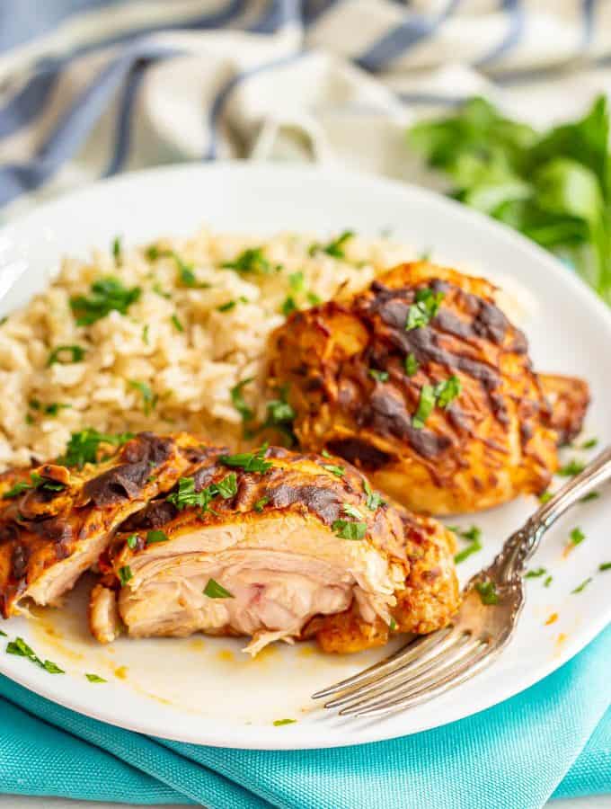 Sliced, cooked chicken thighs with Dijon mustard served on a white plate with rice