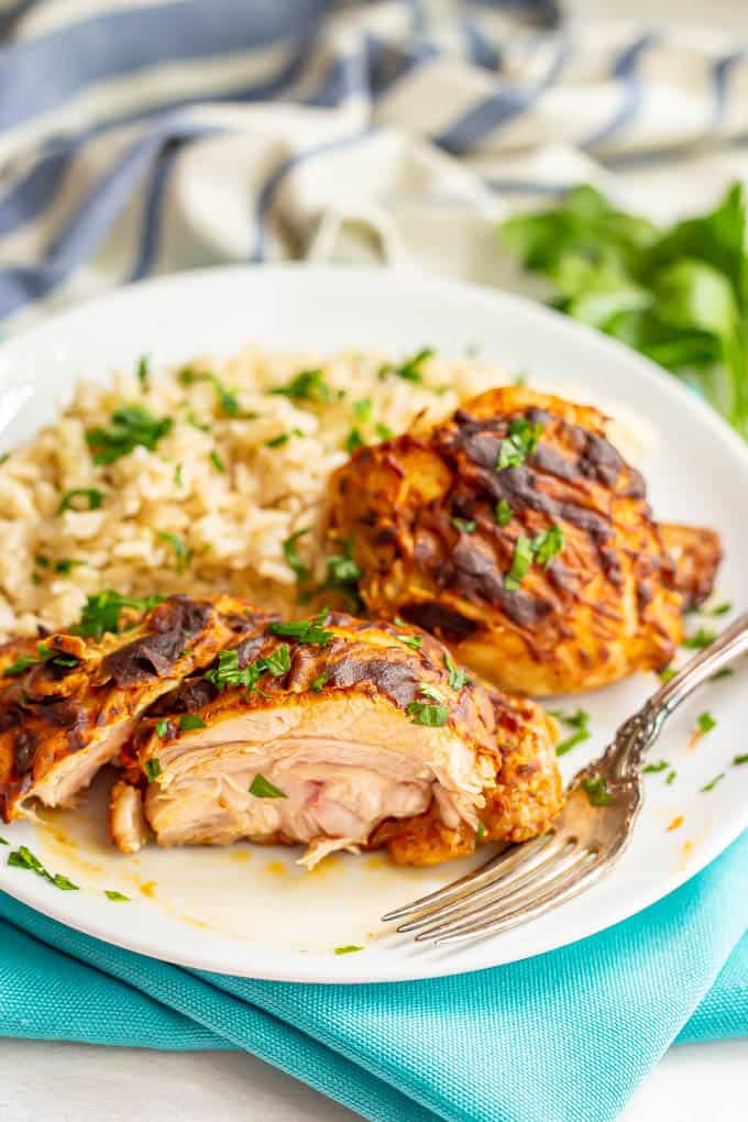 Sliced, cooked chicken thighs with Dijon mustard served on a white plate with rice