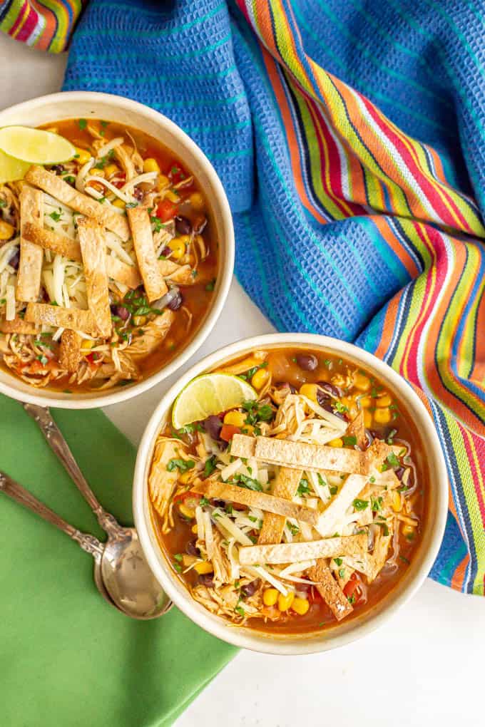 Two bowls served up of homemade chicken tortilla soup with colorful napkins nearby