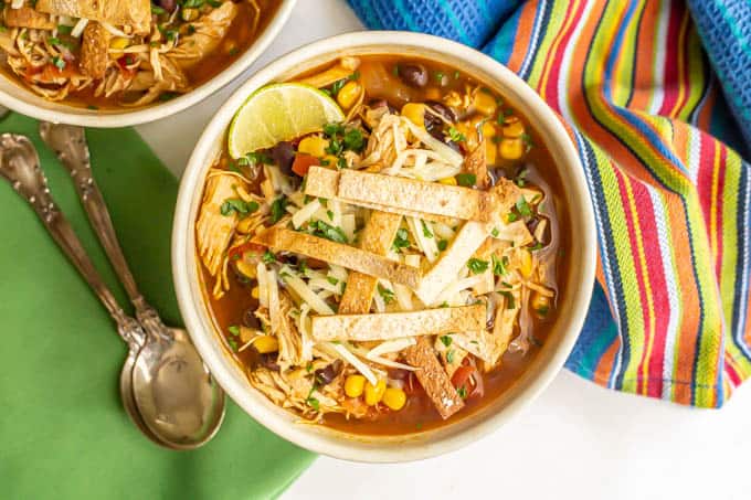 Overhead shot of a bowl of chicken tortilla soup with spoons nearby