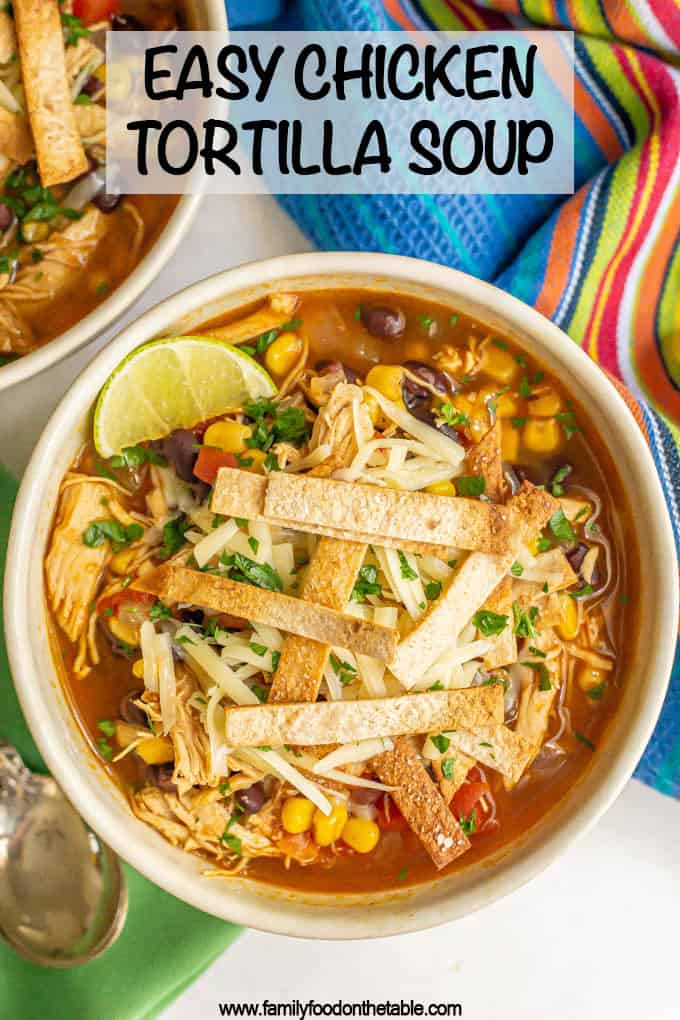 A bowl of chicken tortilla soup with black beans and corn, topped with tortilla strips, cheese and a lime wedge, with a text box overlap
