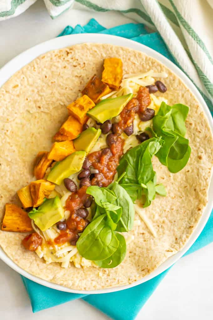 Veggie loaded breakfast burrito on a tortilla on a white plate