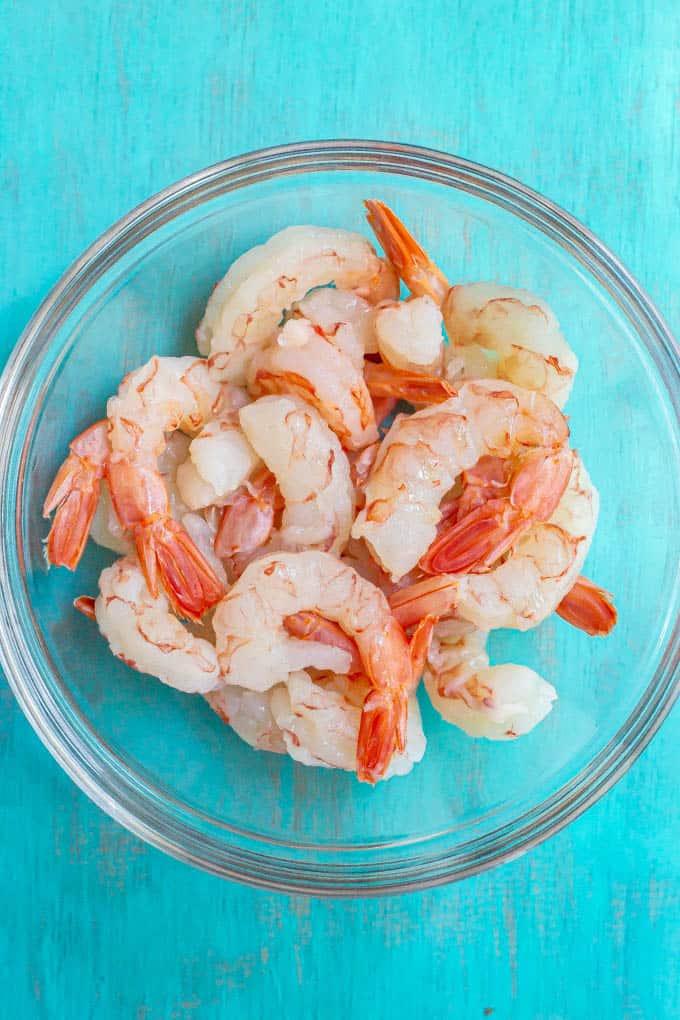 Peeled, deveined extra large raw shrimp in a glass bowl